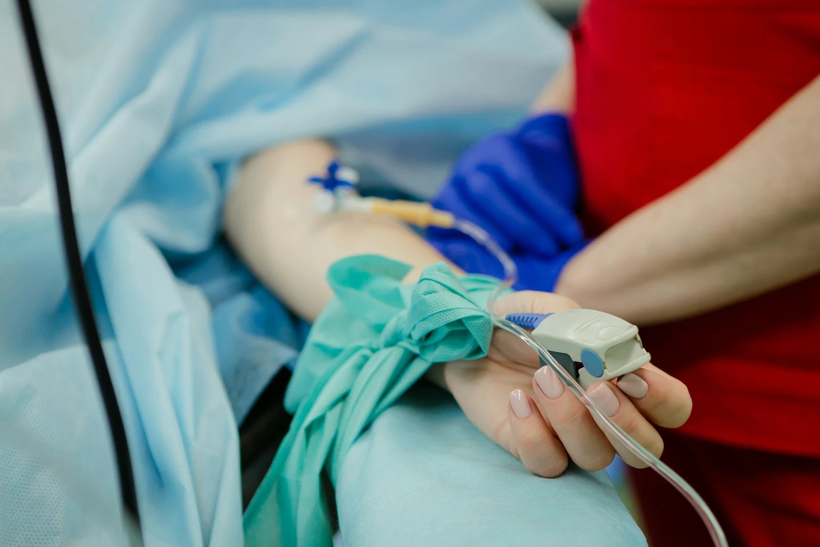 Someone in a hospital bed with an IV and blood oxygen monitor, possibly suffering barbiturate poisoning symptoms.