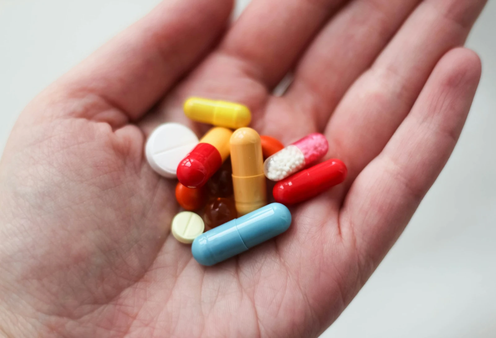 A handful of multicolored pills indicating the possibility of drug interactions, such as between gabapentin and Tylenol.