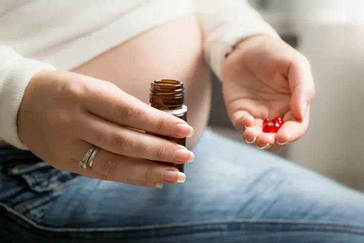 Can You Take Adderall While Pregnant? A pregnant woman holding some pills in one hand and a pill bottle in the other.